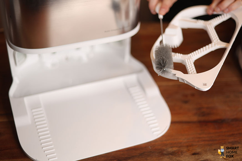 The cleaning tray of the Dreame L10s Ultra base station is wiped down using the cleaning brush.